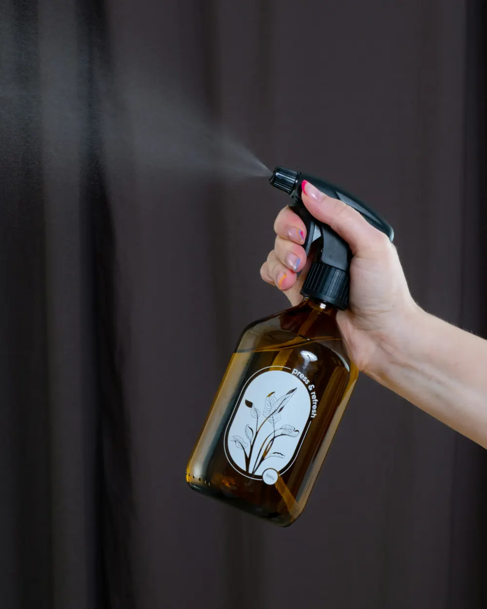 Hand holding an amber glass spray bottle