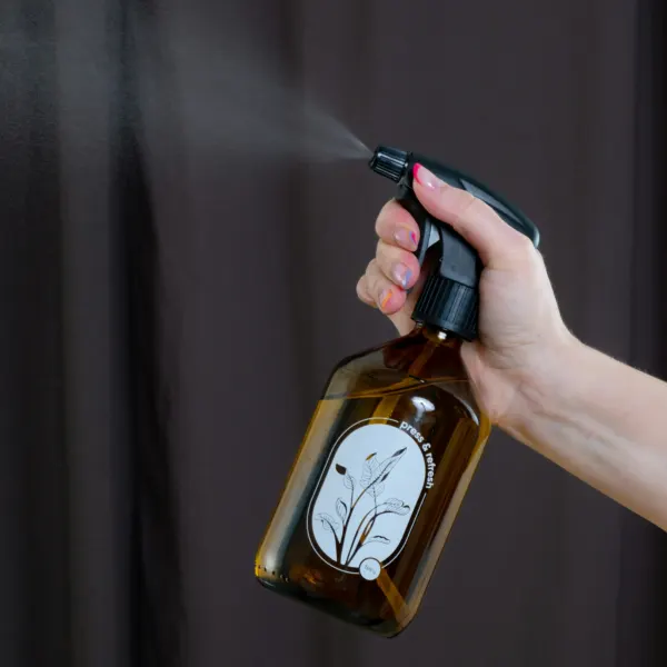 Hand holding an amber glass spray bottle