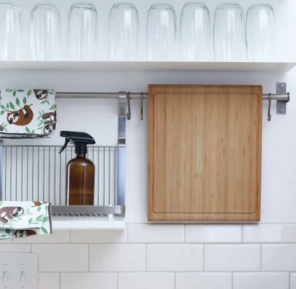 Amber glass spray bottle and bamboo board on a kitchen rail