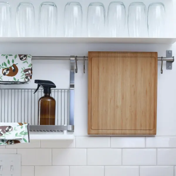 Amber glass spray bottle and bamboo board on a kitchen rail
